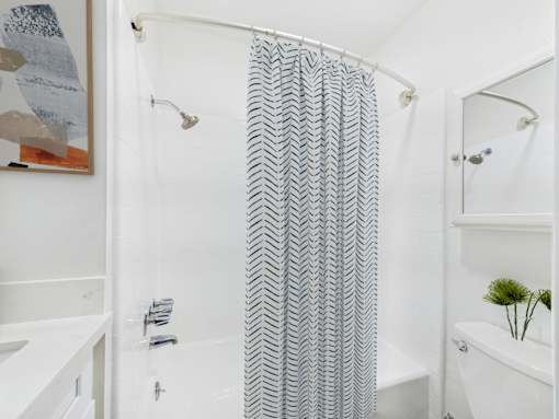 A shower curtain with a zigzag pattern hangs in a white bathroom.