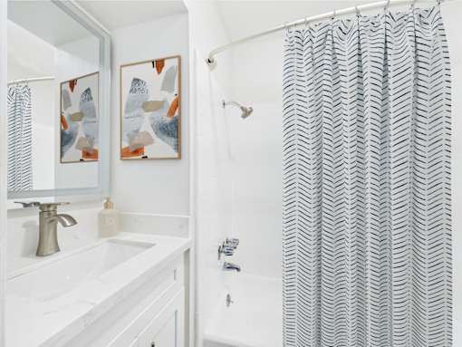A bathroom with a white sink and a shower curtain with a zig zag pattern.