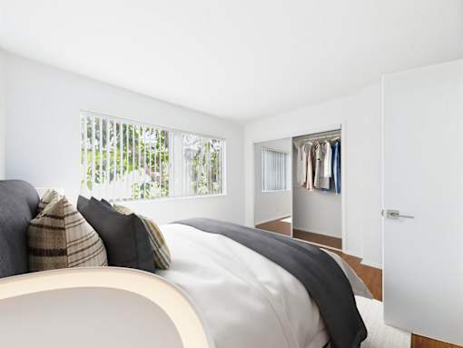 A bedroom with a bed, pillows, and a closet.