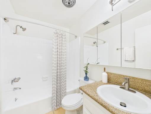 A white bathroom with a toilet, sink, and shower.