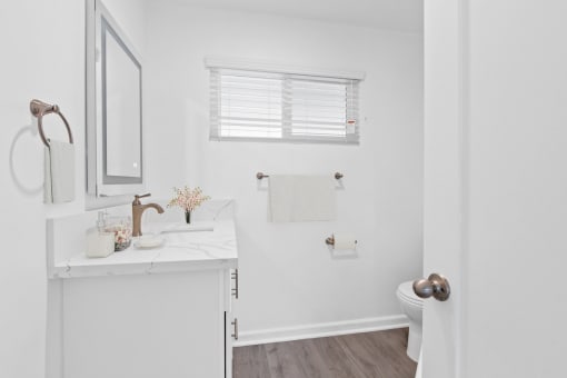 a small bathroom with white walls and wood flooring
