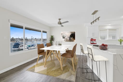 a dining area with a white table and chairs and a large window with a view of a