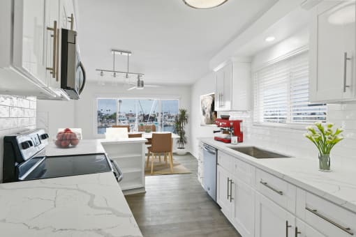 a kitchen with white cabinets and a large window