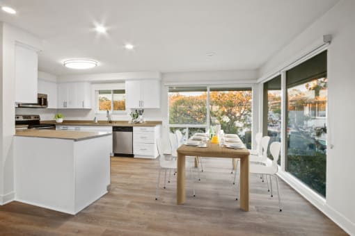 a kitchen with white cabinets and a wooden table with white chairs