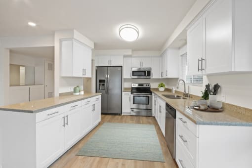 a kitchen with white cabinets and a blue rug