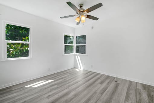 an empty room with white walls and a ceiling fan