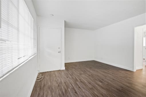 an empty living room with white walls and wood floors