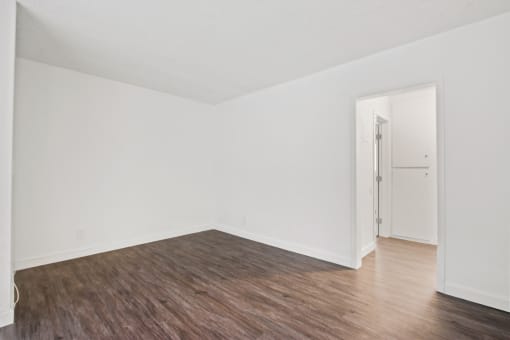 an empty room with wood floors and white walls