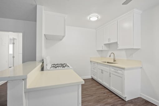 an empty kitchen with white cabinets and white counter tops