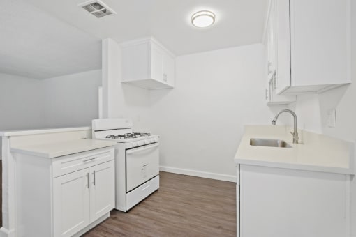 an empty kitchen with white cabinets and a white counter top