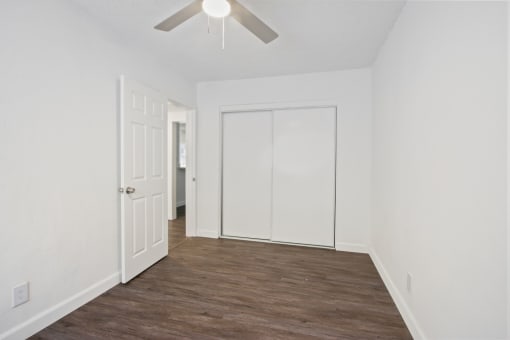 an empty room with white walls and a ceiling fan