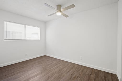 an empty room with white walls and a ceiling fan