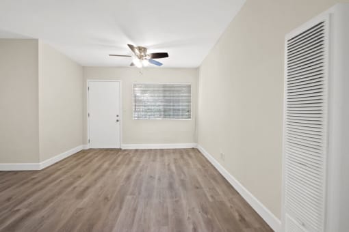 an empty living room with white walls and a ceiling fan