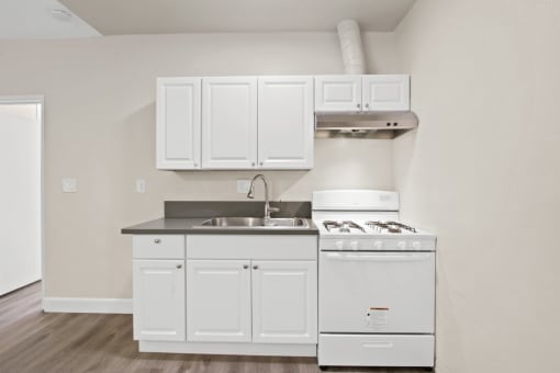 a kitchen with white cabinets and a stove and a sink