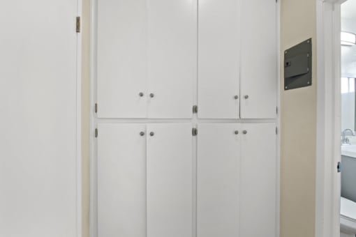 a row of white closet doors in a bathroom
