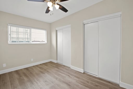 an empty bedroom with a ceiling fan and a closet