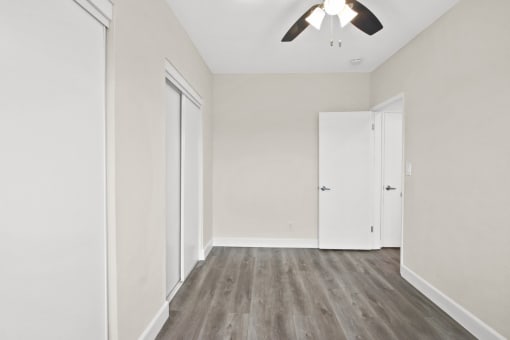 an empty room with white walls and a ceiling fan