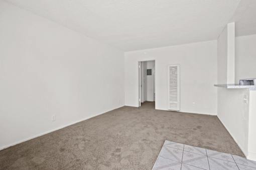 an empty living room with white walls and carpet and a white door