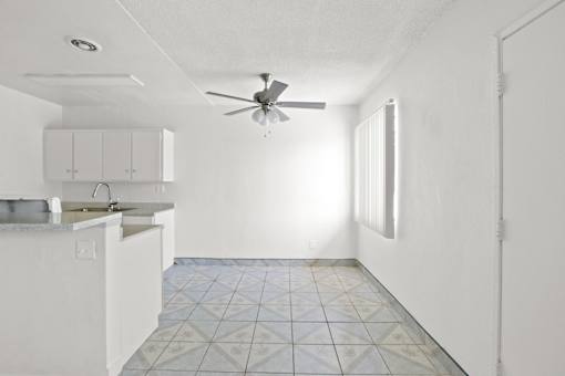 an empty kitchen with white cabinets and a ceiling fan