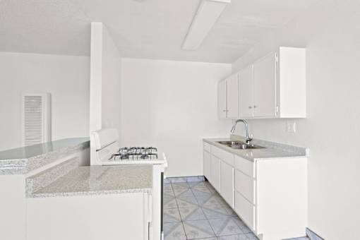 an empty kitchen with white cabinets and a counter top
