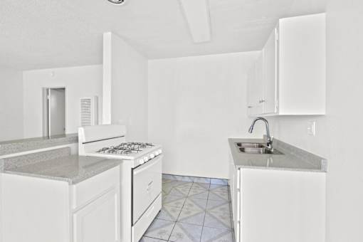 a kitchen with white cabinets and a sink and a stove