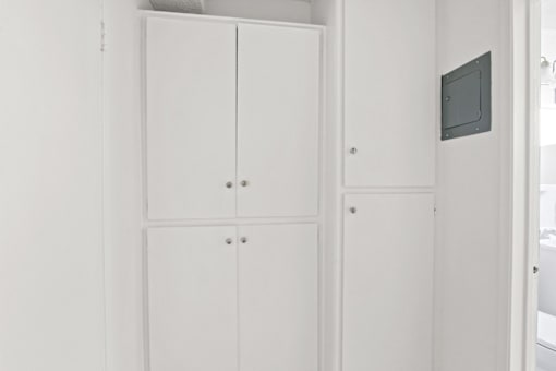 a row of white wardrobes in a white room with a television