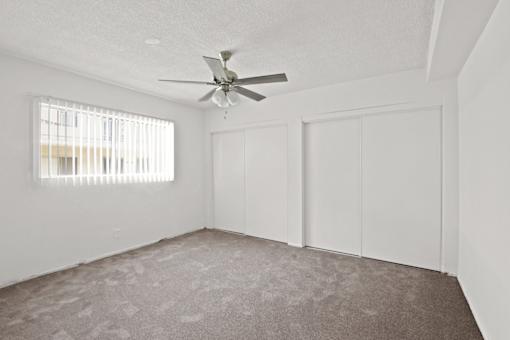 an empty living room with white walls and a ceiling fan