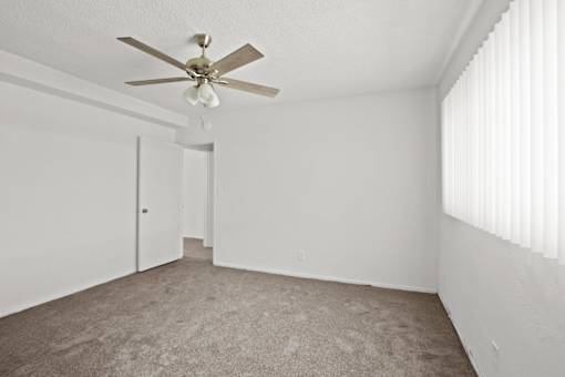 an empty living room with a ceiling fan and white walls