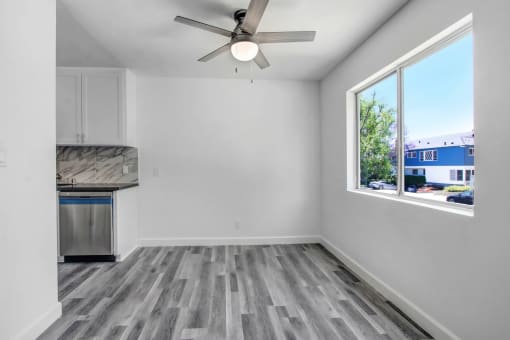 an empty room with a large window and a ceiling fan