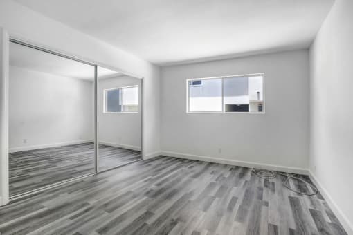 a bedroom with hardwood floors and white walls