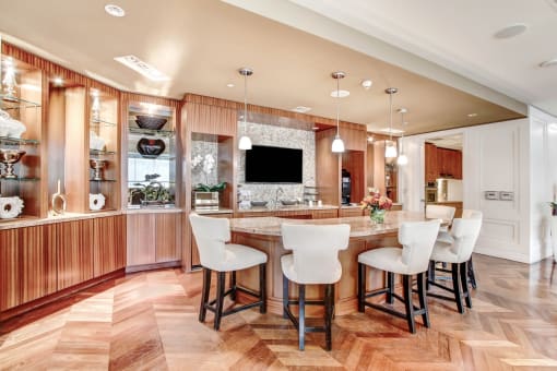 a kitchen with a large island with bar chairs and a tv