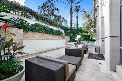 a patio with chairs and plants and a wall
