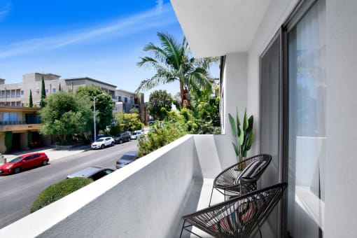 a balcony with two chairs and a plant