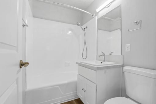 A white bathroom with a toilet, sink, and bathtub.