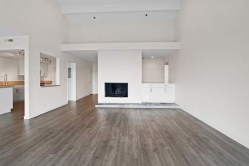 A large, empty room with a fireplace and wooden floors.