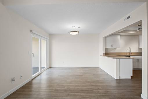 A spacious room with a kitchen area and wooden flooring.