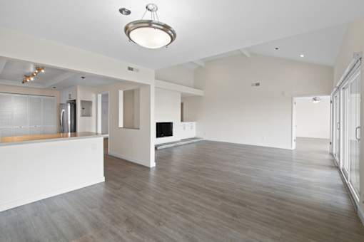 A spacious living room with a kitchen area in the background.