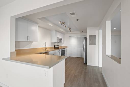 A modern kitchen with white cabinets and a wooden floor.