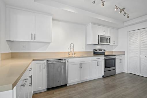A modern kitchen with white cabinets and stainless steel appliances.