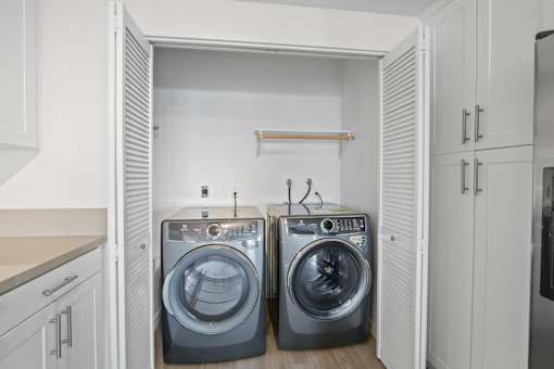 A laundry room with two washing machines and a shelf.