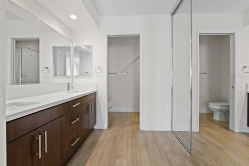 A bathroom with a white counter top and wooden floors.