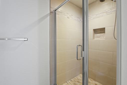 A shower stall with a glass door and a handle.