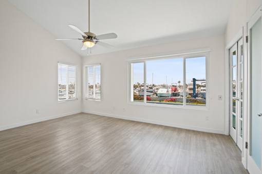 A room with a ceiling fan and a view of the city.