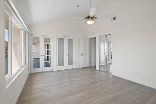 A spacious room with a ceiling fan and sliding glass doors.