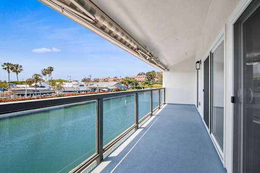 A long hallway with a view of a body of water and palm trees.