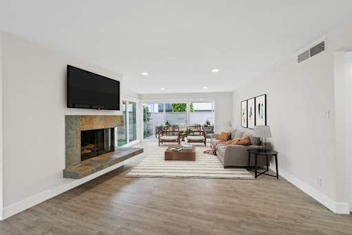 A modern living room with a fireplace and a flat screen TV mounted on the wall.