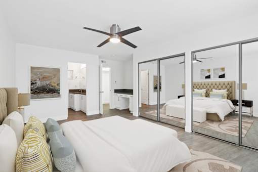 A bedroom with a bed, a couch, and a ceiling fan.