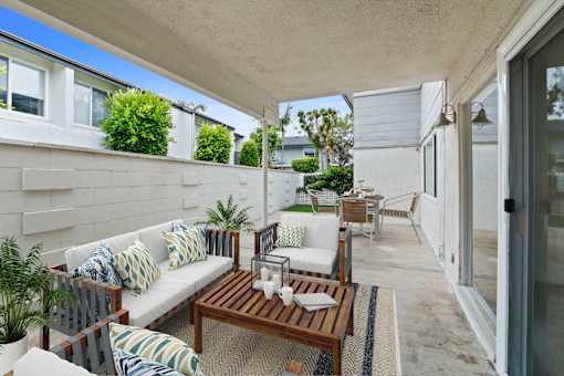 A patio with a white couch and a wooden table.