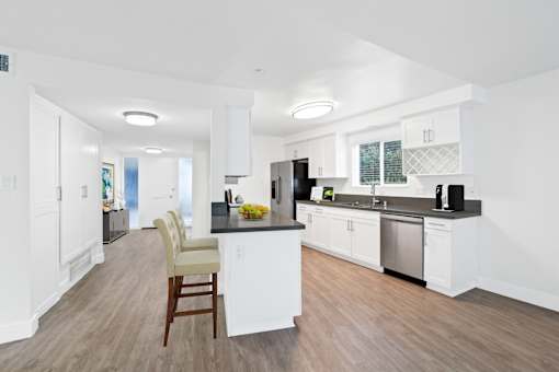 A kitchen with white cabinets and a wooden floor.