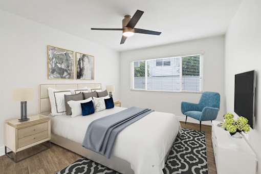 A bedroom with a bed, chair, and ceiling fan.